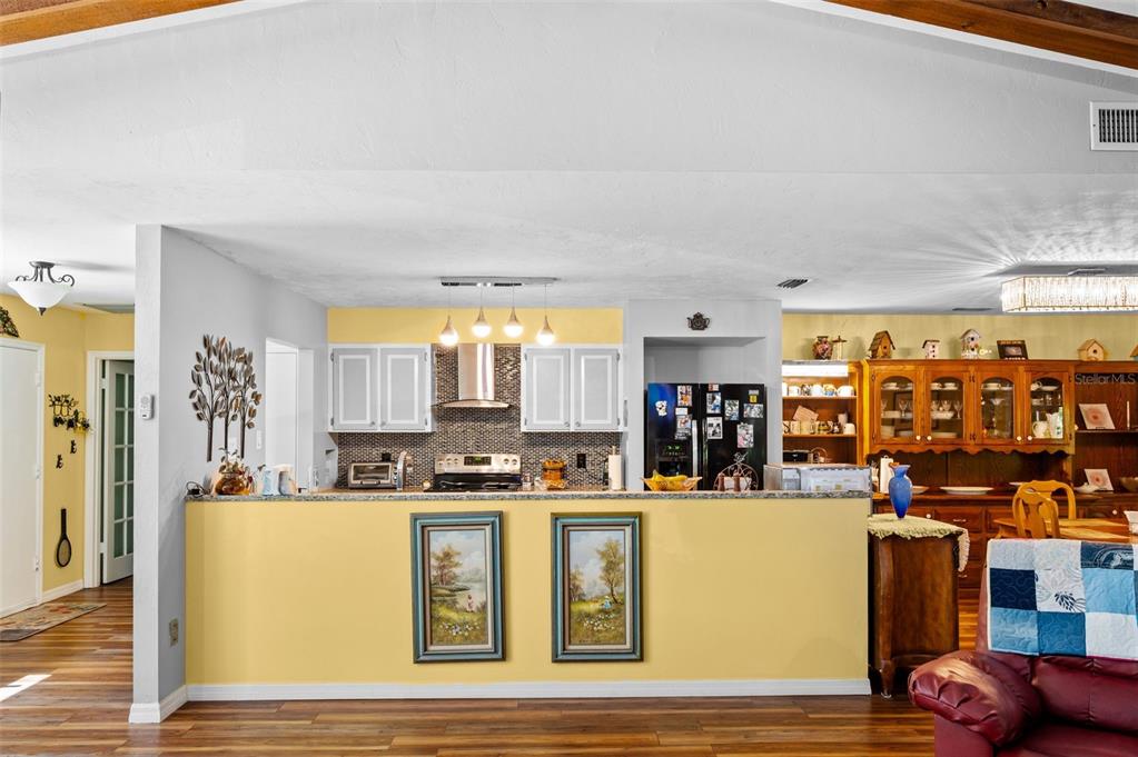 A kitchen with yellow walls, white cabinets, and a peninsula overlooks a living area — 16422 NE 10TH STREET, GAINESVILLE, FL