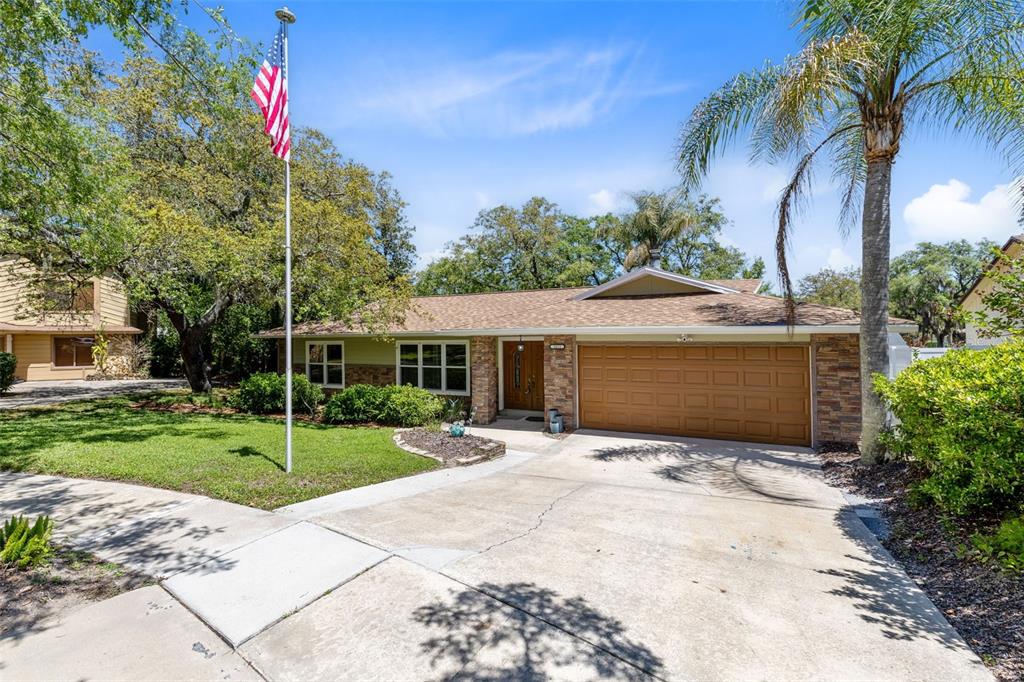 A single-story house with a brown garage door, stone accents, and a front yard flagpole — 2611 TAMERA COURT, APOPKA, FL