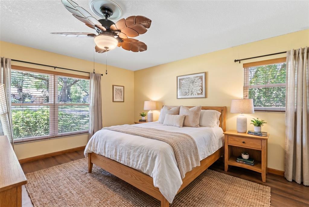 A bedroom with yellow walls, a wooden bed frame, a ceiling fan, and two windows — 2611 TAMERA COURT, APOPKA, FL