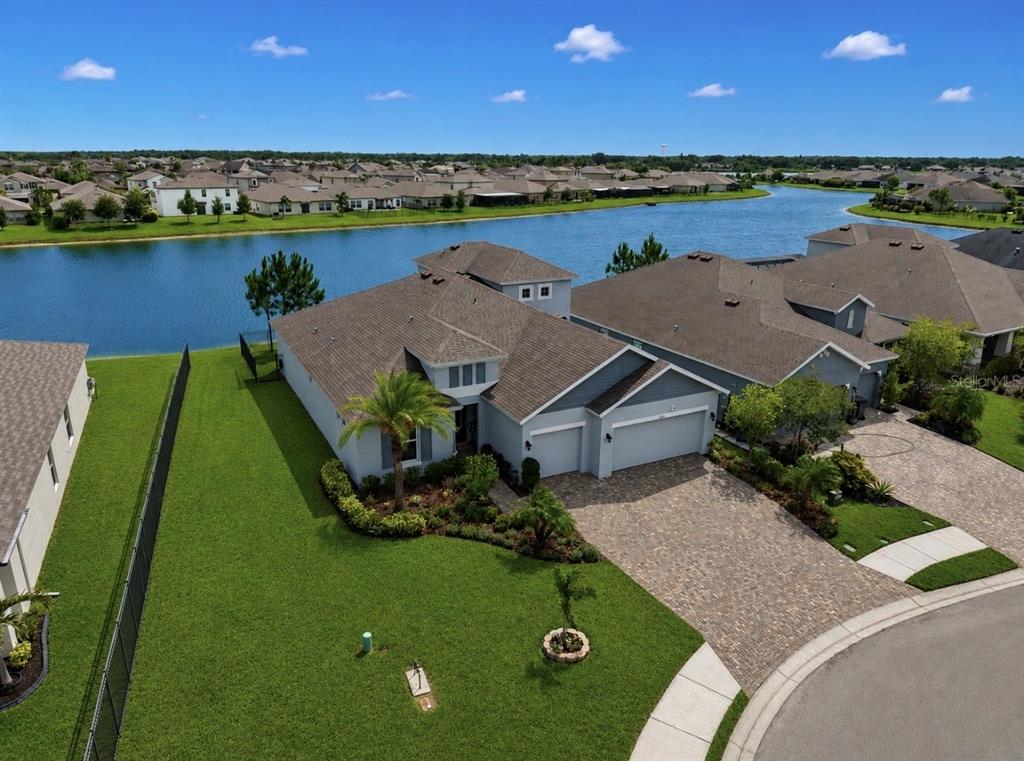 An aerial view shows a suburban house with a paved driveway, lawn, and lakefront backyard — 5206 GAVELLA COVE, PALMETTO, FL