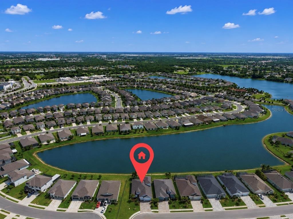 An aerial view shows a suburban house with a red location pin by a lake — 5206 GAVELLA COVE, PALMETTO, FL