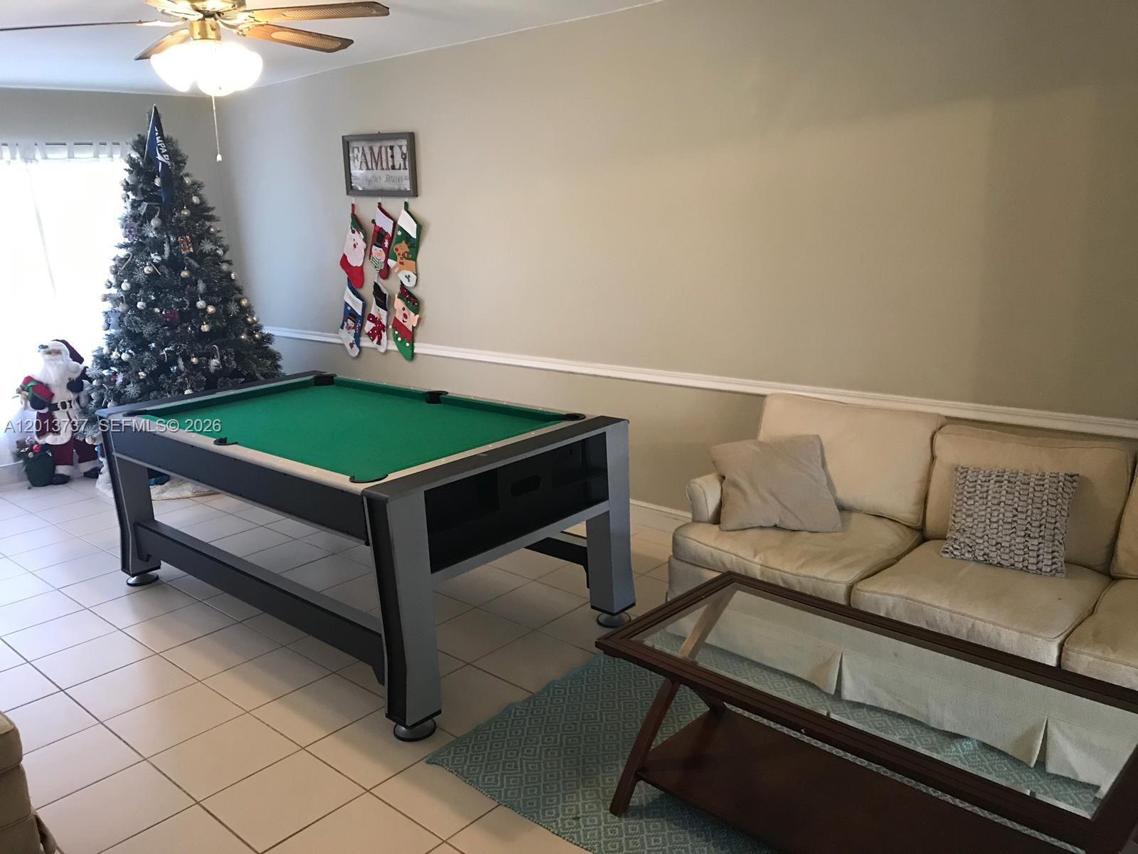 A living room features a pool table, a beige sofa, a coffee table, and a Christmas tree — 3965 NW 9th Ave # 3, Deerfield Beach FL 33064, DEERFIELD BEACH, FL