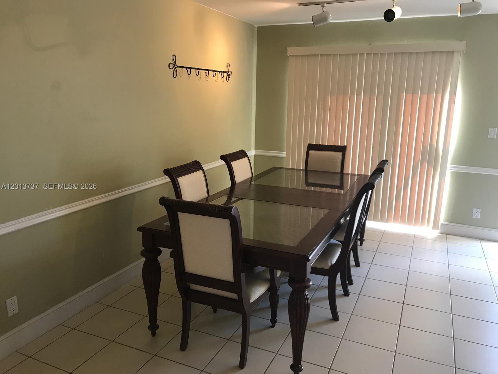 A dining room features a dark wood table with glass inserts and six upholstered chairs — 3965 NW 9th Ave # 3, Deerfield Beach FL 33064, DEERFIELD BEACH, FL