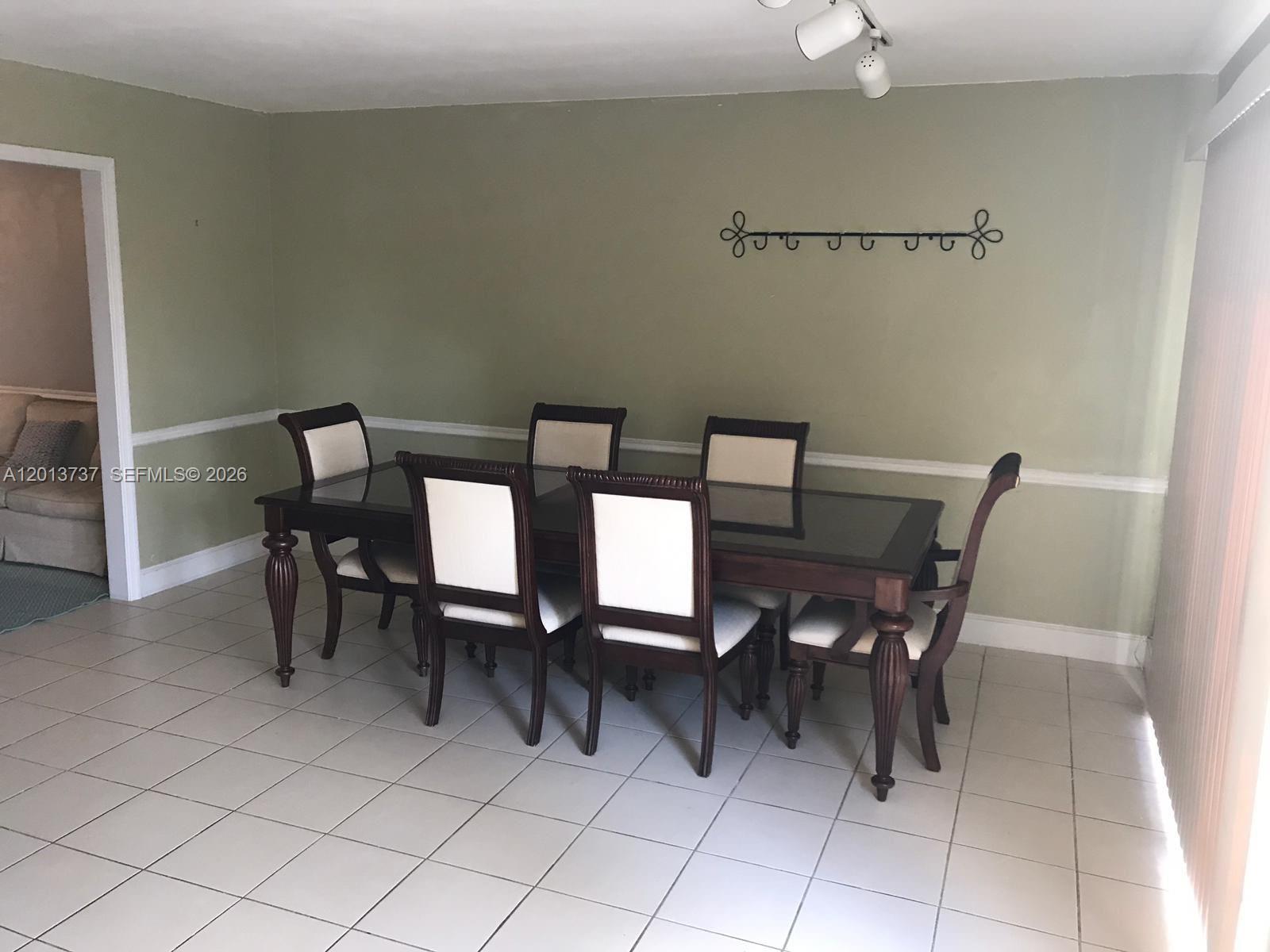 A dining room features a dark wood table with six upholstered chairs on tile flooring — 3965 NW 9th Ave # 3, Deerfield Beach FL 33064, DEERFIELD BEACH, FL