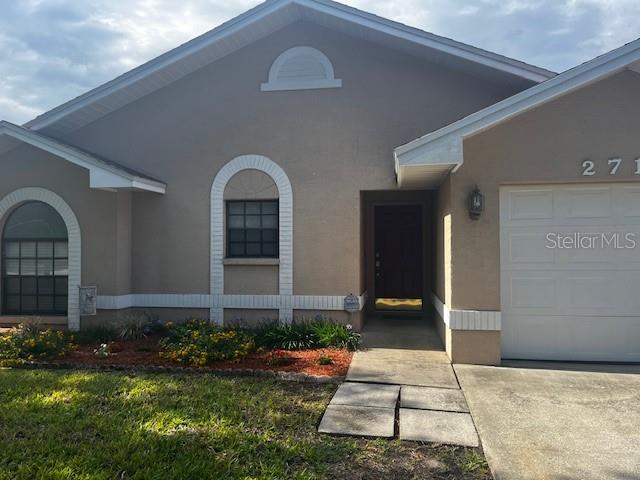 The exterior of a tan, single-story house features a garage and a front entrance — 2717 WILDER PARK DRIVE, PLANT CITY, FL