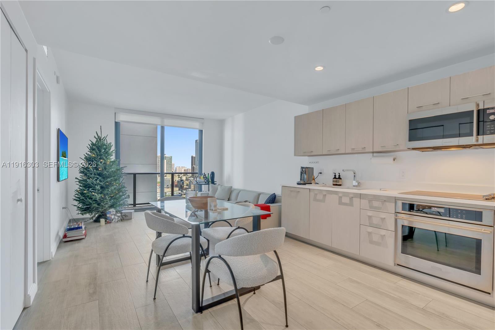 A modern apartment features a kitchen with light wood cabinets, a dining area, and a balcony — 55 SW 9th St # 2610, Miami FL 33130, MIAMI, FL