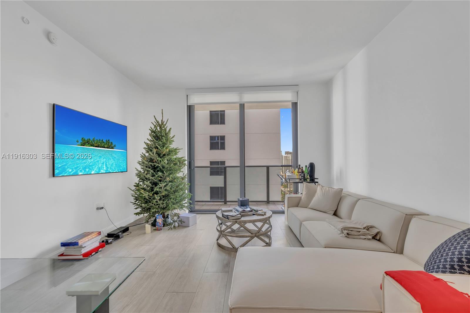 A modern living room features a white sectional sofa, a Christmas tree, and a balcony — 55 SW 9th St # 2610, Miami FL 33130, MIAMI, FL