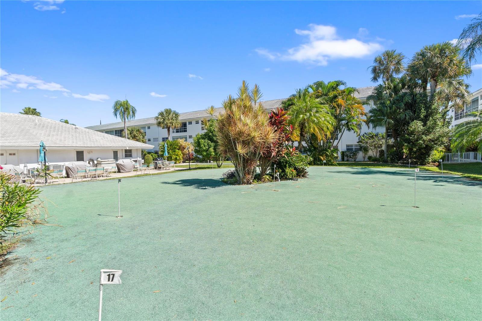A putting green with numbered flags sits in front of a multi-story residential building — 2050 NE 39th Street # 302e, Lighthouse Point FL 33064, LIGHTHOUSE POINT, FL