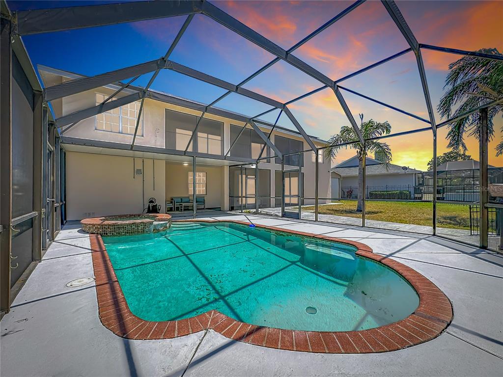 A screened-in swimming pool and hot tub sit on a patio behind a two-story house — 624 KINGSTON COURT, APOLLO BEACH, FL