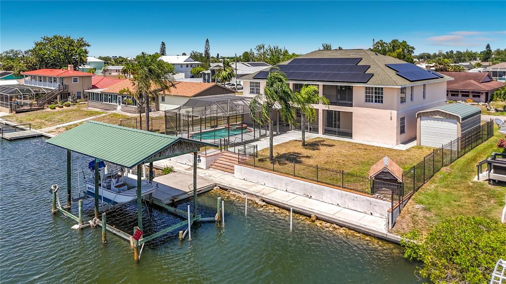 An aerial view of a waterfront house with a boat lift, pool, and solar panels — 624 KINGSTON COURT, APOLLO BEACH, FL