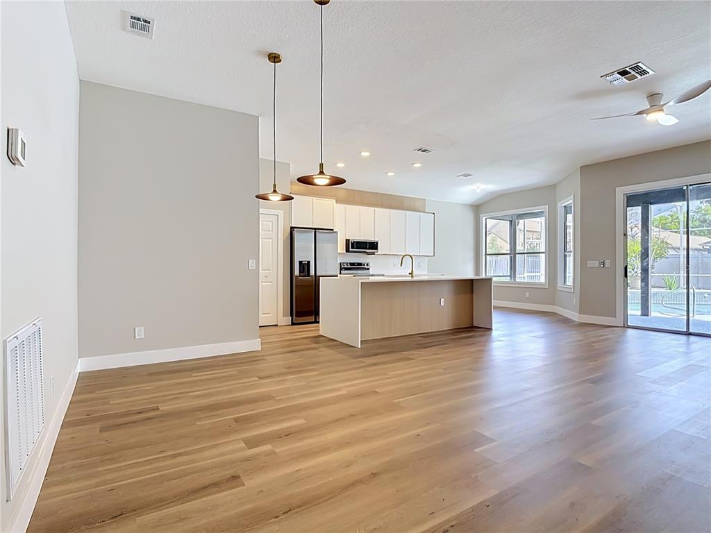 A modern open-concept kitchen features white cabinetry, a wood-paneled island, and light hardwood flooring — 5013 TERRA VISTA WAY, ORLANDO, FL