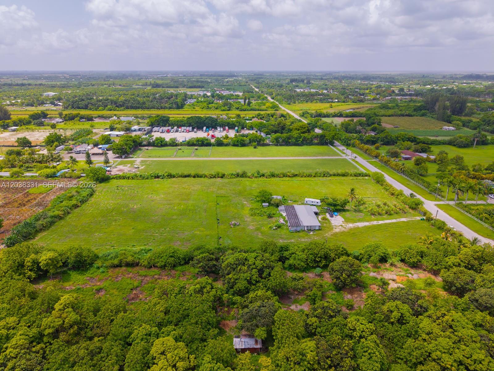 An aerial view shows a rural property with a house, outbuildings, and surrounding green fields — 12825 SW 197 AVE, Miami FL 33196, MIAMI, FL
