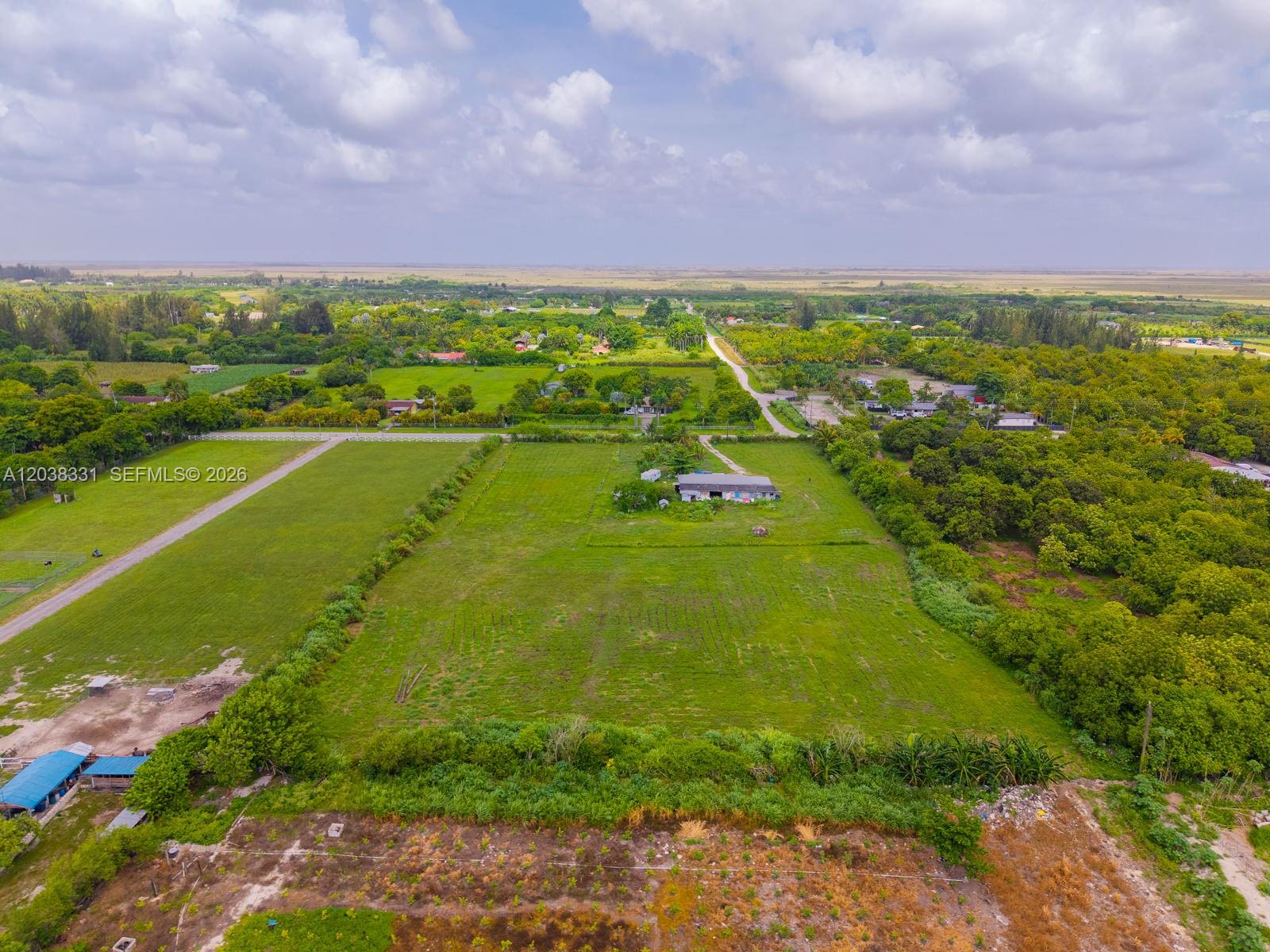 An aerial view shows a large, flat, grassy lot with a house and surrounding trees — 12825 SW 197 AVE, Miami FL 33196, MIAMI, FL