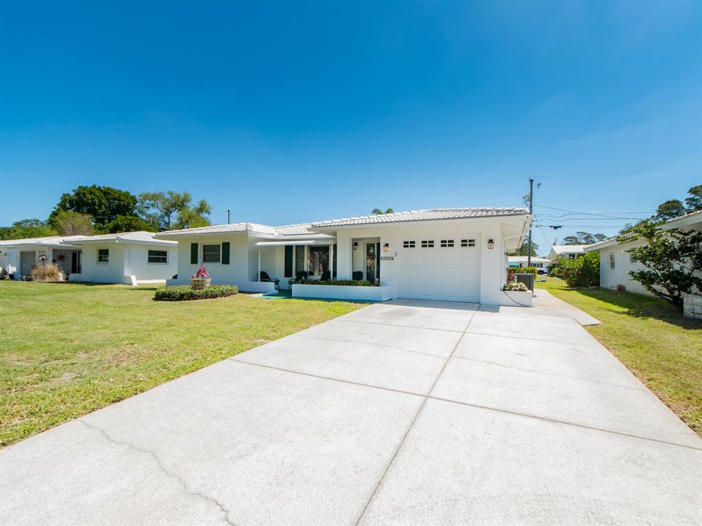 A white single-story house with a concrete driveway and a two-car garage — 9227 143RD STREET, SEMINOLE, FL