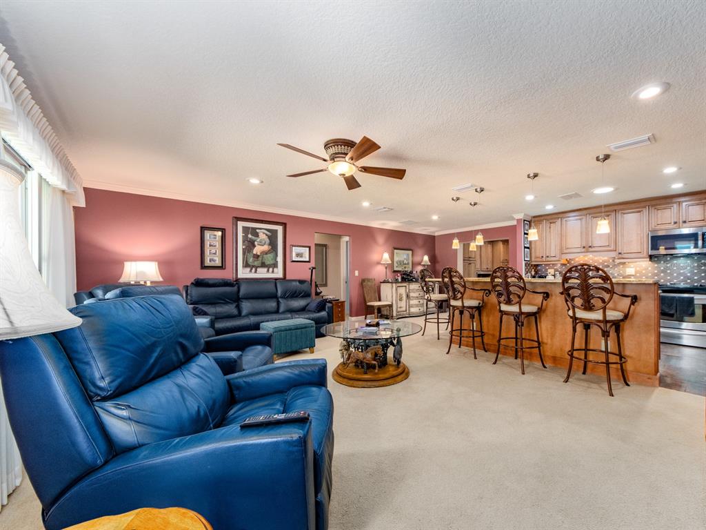 A living room with blue leather furniture, a glass coffee table, and an open kitchen — 9227 143RD STREET, SEMINOLE, FL