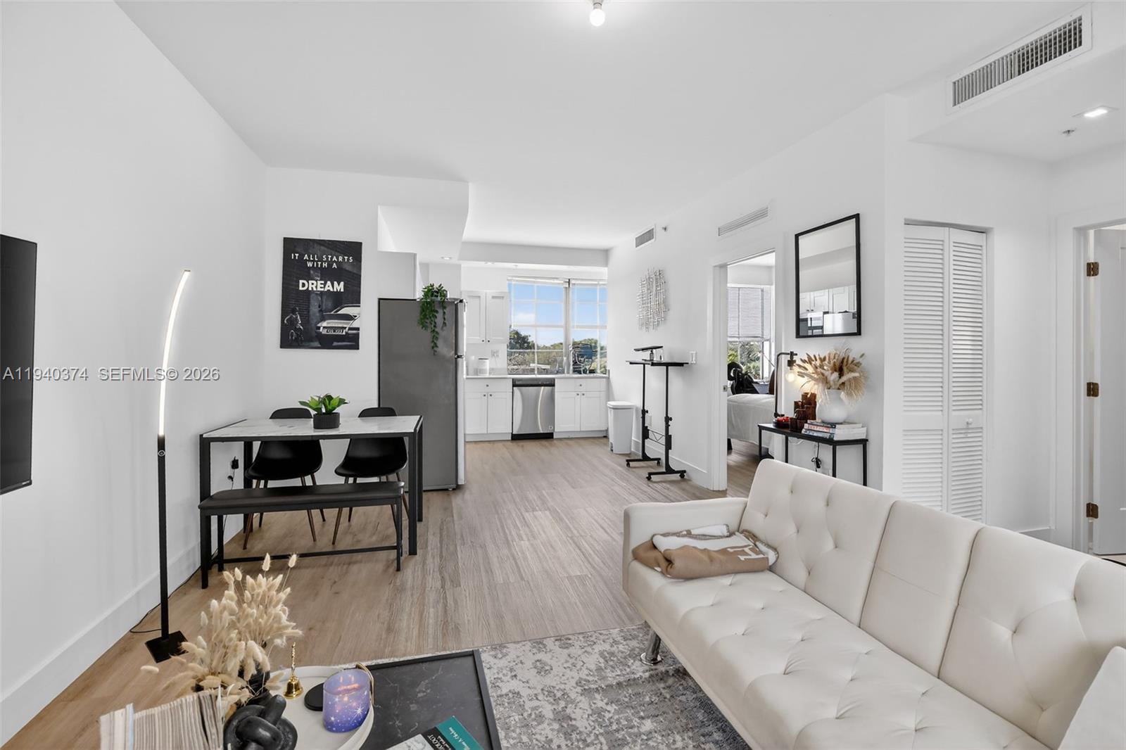 A bright, open-concept living and dining area features white walls, light wood flooring, and modern furniture — 4100 SW 64th Ave # 301, Davie FL 33314, DAVIE, FL