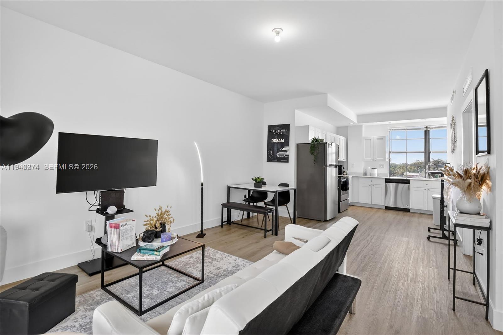 An open-concept living room and kitchen area with white walls and light wood flooring — 4100 SW 64th Ave # 301, Davie FL 33314, DAVIE, FL