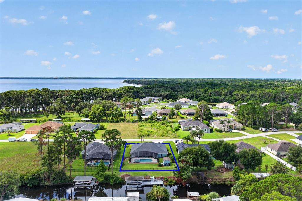 An aerial view shows a residential house with a screened pool near a lake — 12037 EAGLE POINT CT, LEESBURG, FL