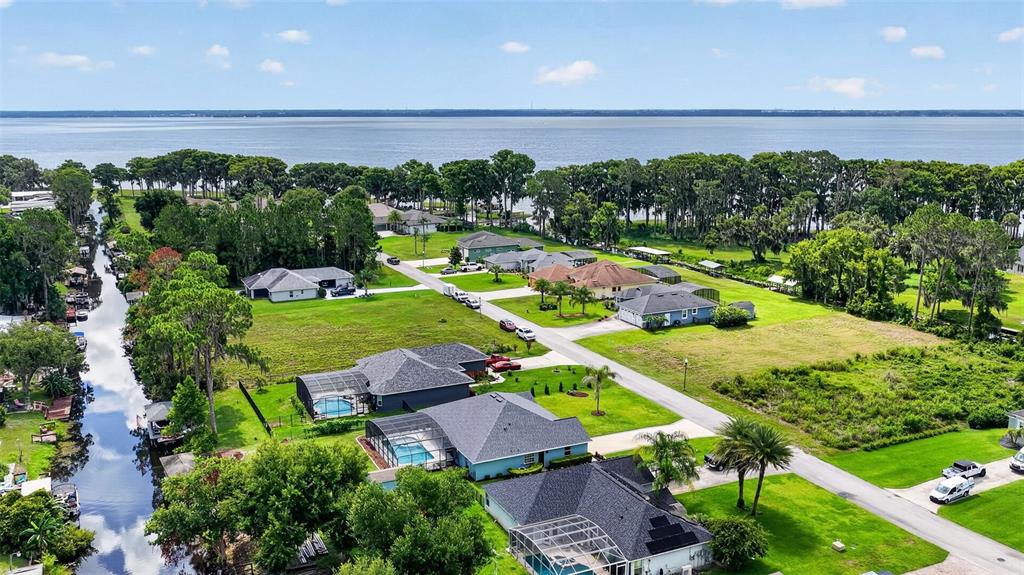 An aerial view shows several houses with swimming pools near a canal and a large lake — 12037 EAGLE POINT CT, LEESBURG, FL