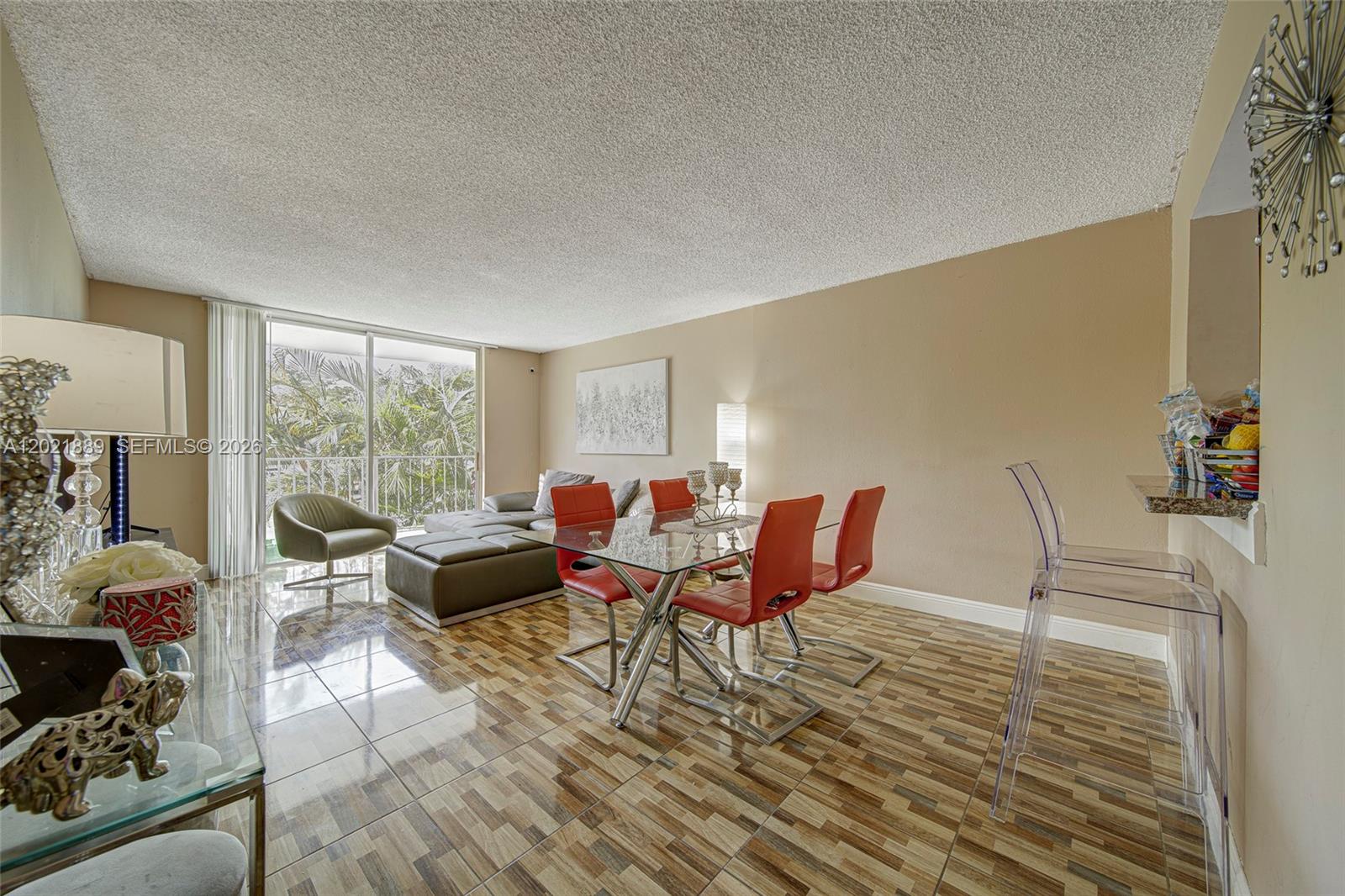 A living and dining area features tile flooring, red chairs, a glass table, and balcony access — 494 NW 165th St Rd # 205, Miami FL 33169, MIAMI, FL