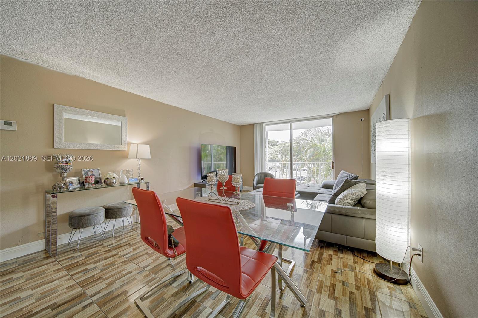 A dining area with a glass table and red chairs sits beside a living room — 494 NW 165th St Rd # 205, Miami FL 33169, MIAMI, FL