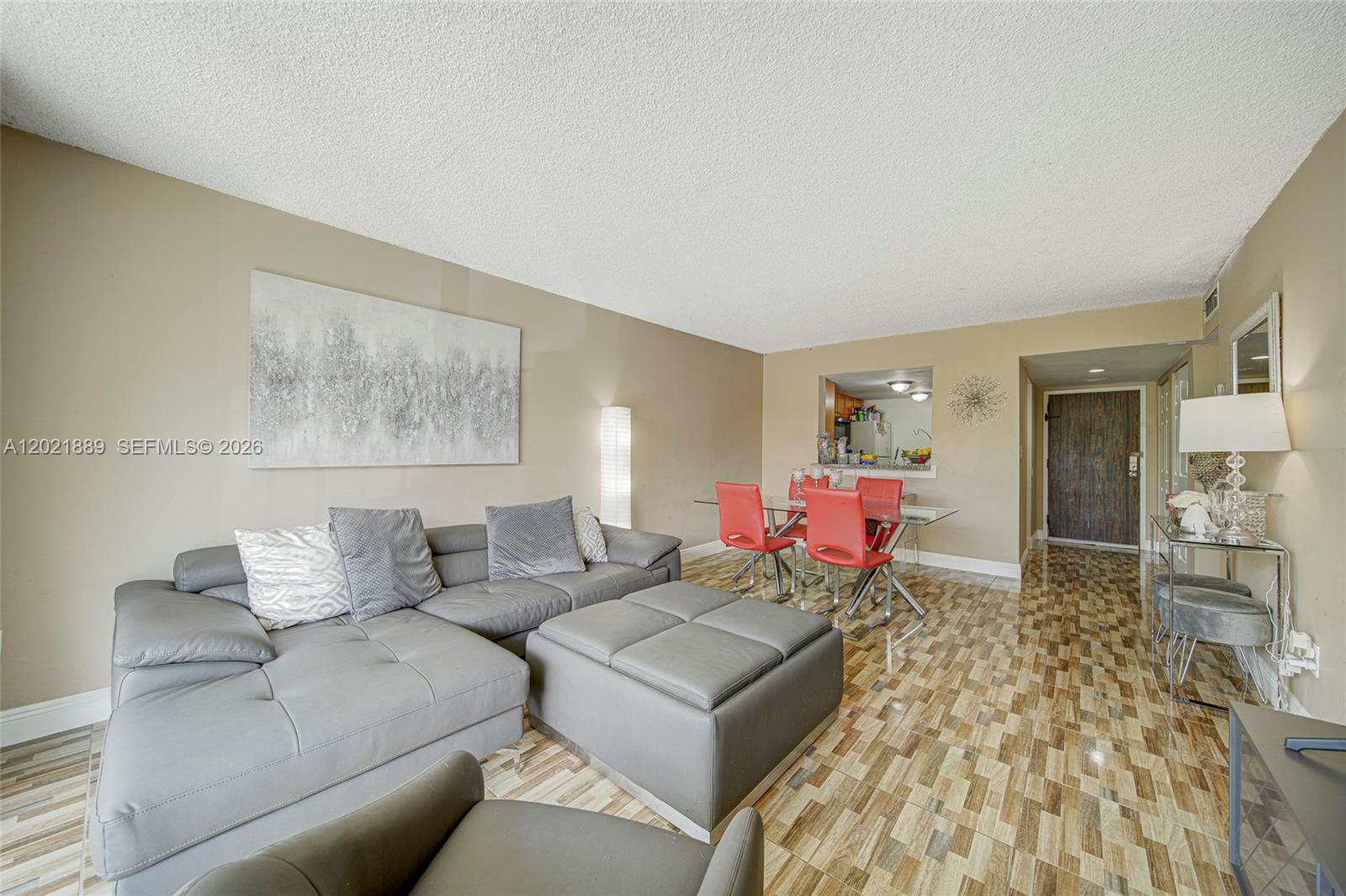 A living and dining area features a gray sectional sofa, red chairs, and tiled floors — 494 NW 165th St Rd # 205, Miami FL 33169, MIAMI, FL