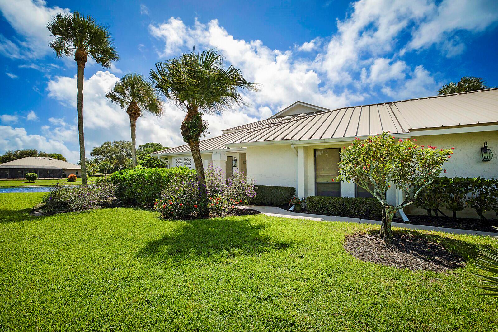 A single-story house with a metal roof, palm trees, and a landscaped lawn — 5611 SE Foxcross Place # 5611, Stuart FL 34997, STUART, FL