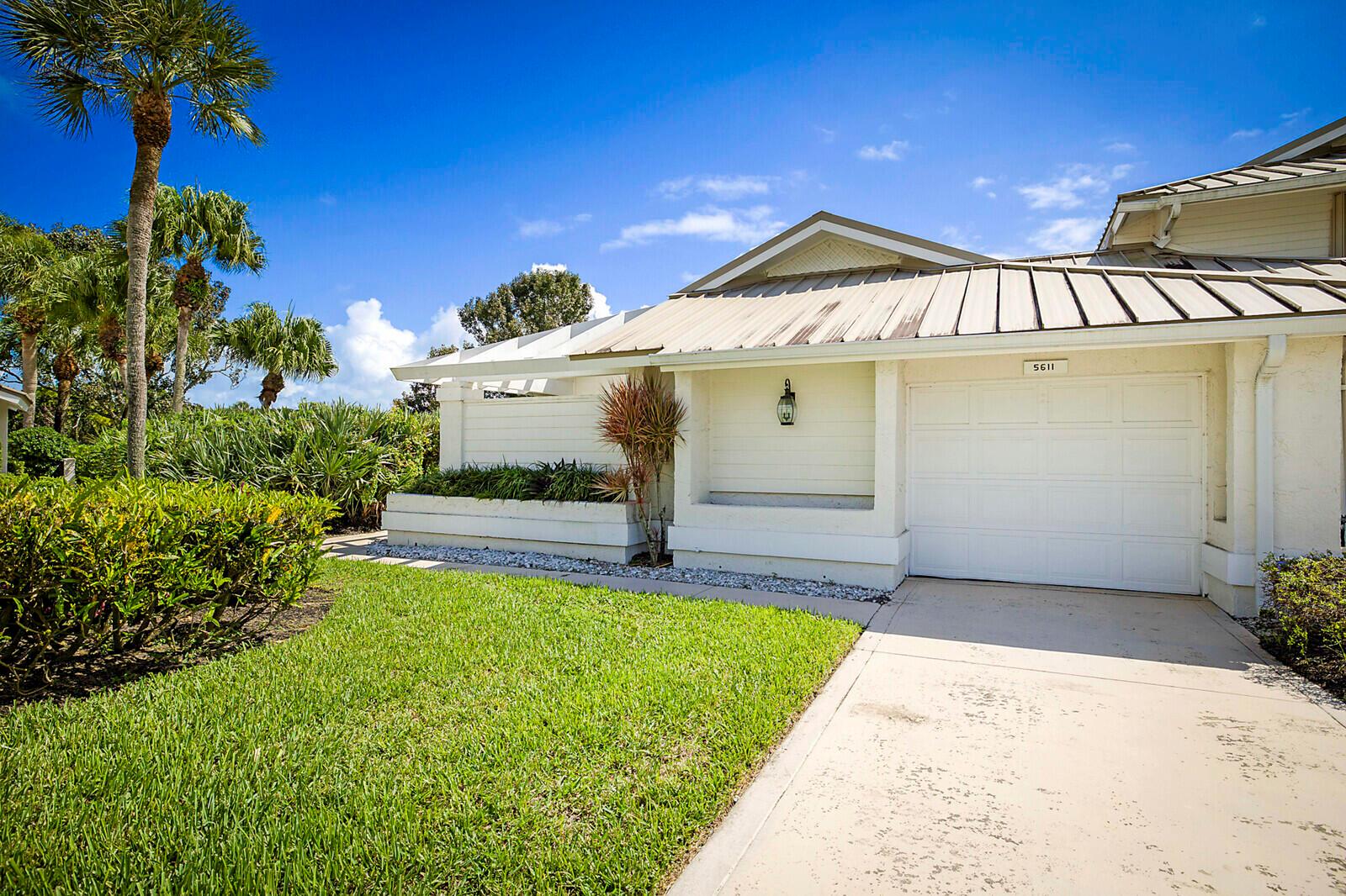 A white house with a metal roof and a garage sits next to a lawn — 5611 SE Foxcross Place # 5611, Stuart FL 34997, STUART, FL