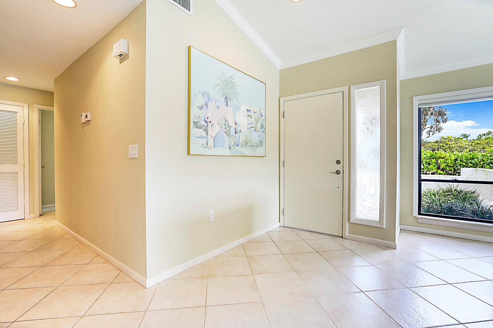 An entryway features beige tile flooring, a white front door, and a large abstract painting — 5611 SE Foxcross Place # 5611, Stuart FL 34997, STUART, FL