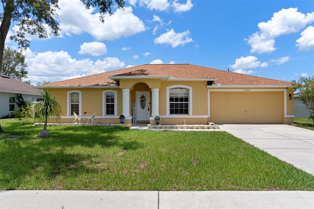 A yellow single-story house with a two-car garage and a covered front entryway — 15437 DEER PATH DRIVE, BROOKSVILLE, FL