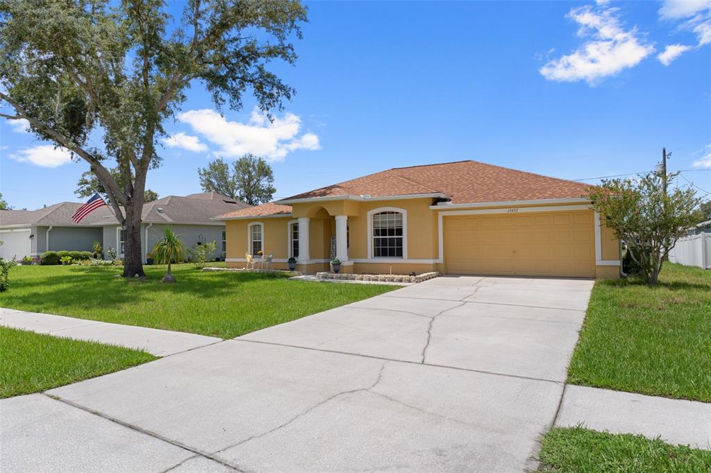 A yellow single-story house with a two-car garage and a concrete driveway — 15437 DEER PATH DRIVE, BROOKSVILLE, FL