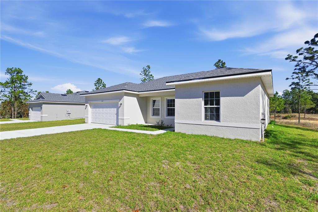 A white single-story house with black trim and a two-car garage sits on a lawn — 6615 N WAYCROSS WAY, CITRUS SPRINGS, FL