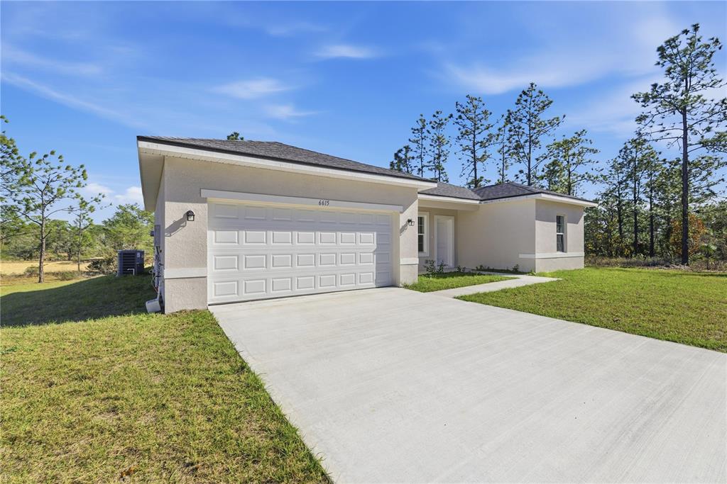 A white single-story house with a black roof and garage door sits on a grassy lot — 6615 N WAYCROSS WAY, CITRUS SPRINGS, FL