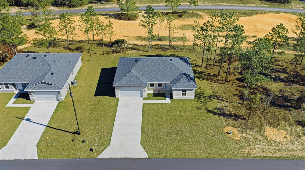 An aerial view shows two modern single-story houses with black roofs and concrete driveways — 6615 N WAYCROSS WAY, CITRUS SPRINGS, FL