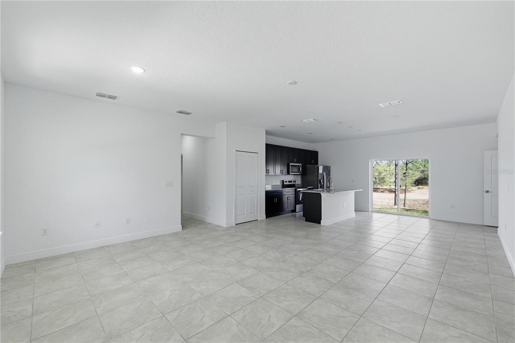 A spacious, open-concept room features white walls, light tile flooring, and a modern kitchen — 6615 N WAYCROSS WAY, CITRUS SPRINGS, FL