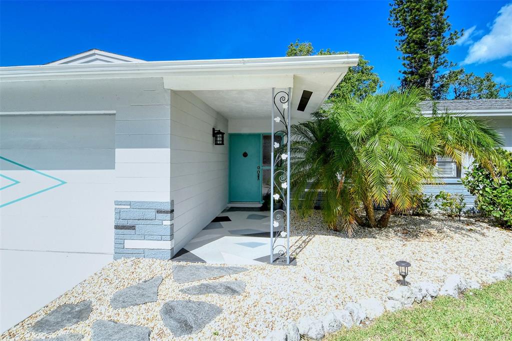 The exterior of a house features a turquoise front door, a decorative metal post, and gravel — 6758 S LOCKWOOD RIDGE ROAD, SARASOTA, FL