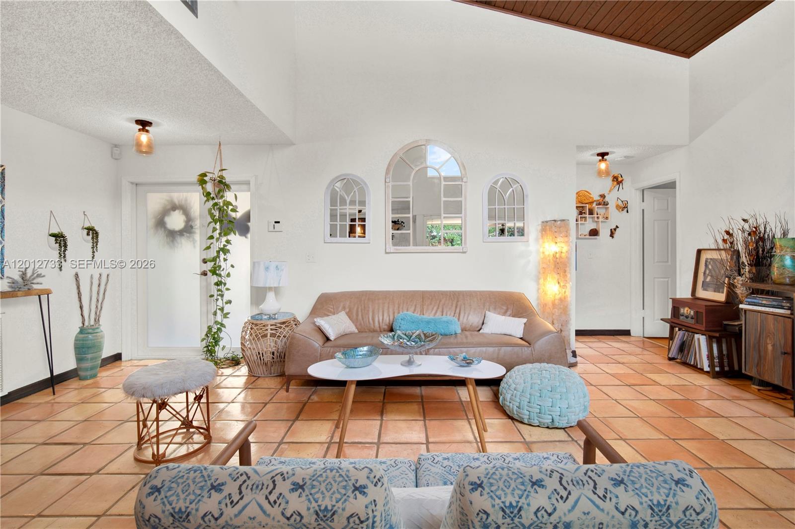 A living room features a vaulted ceiling, tile flooring, a leather sofa, and arched mirrors — 13455 SW 104th Ter, Miami FL 33186, MIAMI, FL