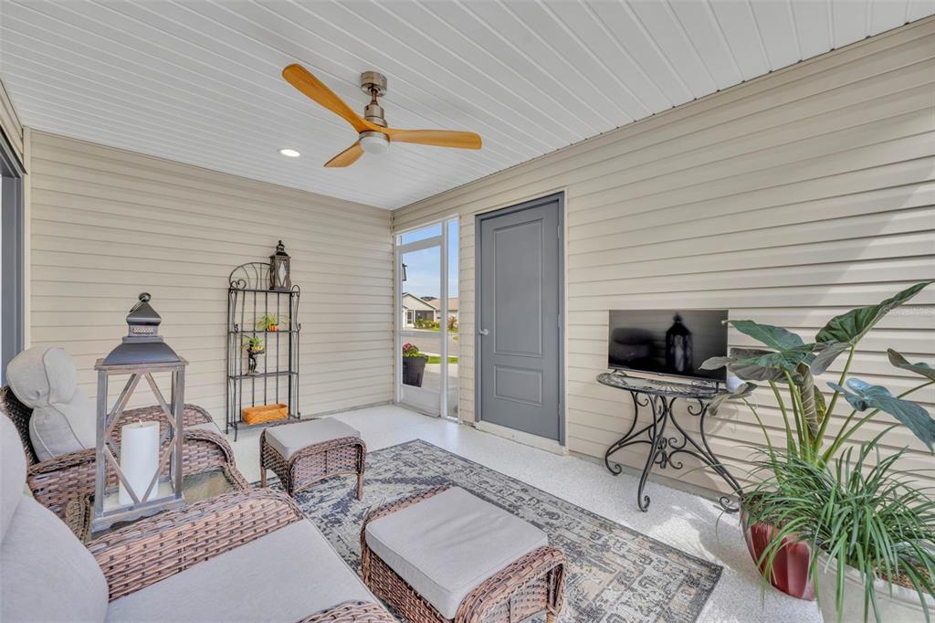 A covered patio features wicker furniture, a ceiling fan, and a television on a metal stand — 1640 OLIVIA TERRACE, THE VILLAGES, FL