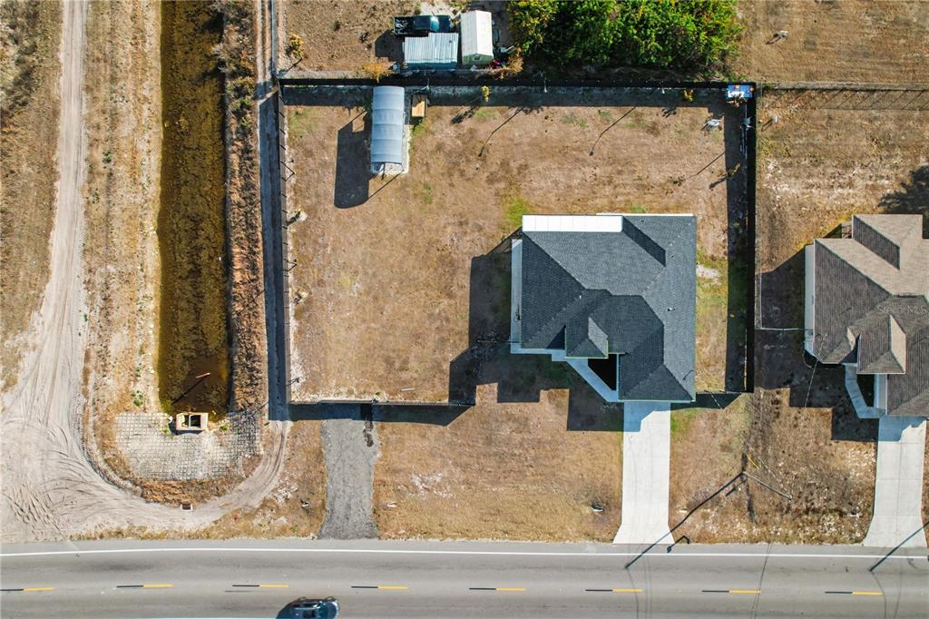 An aerial view shows a house with a large fenced yard and a gravel driveway — 3705 23RD STREET SW, LEHIGH ACRES, FL