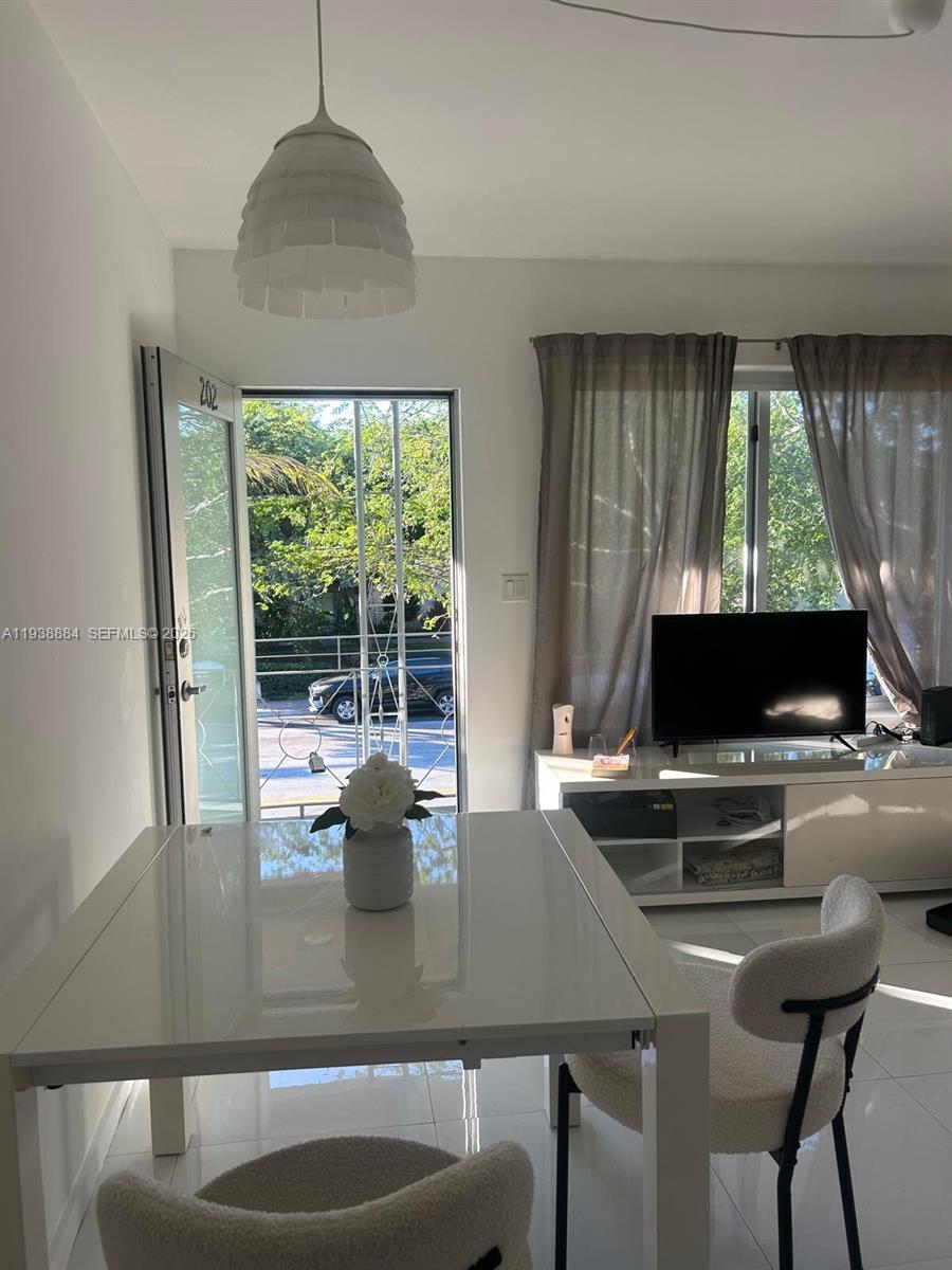 A dining area with a white table and chairs sits before a door and window — 801 15th St # 202, Miami Beach FL 33139, MIAMI BEACH, FL