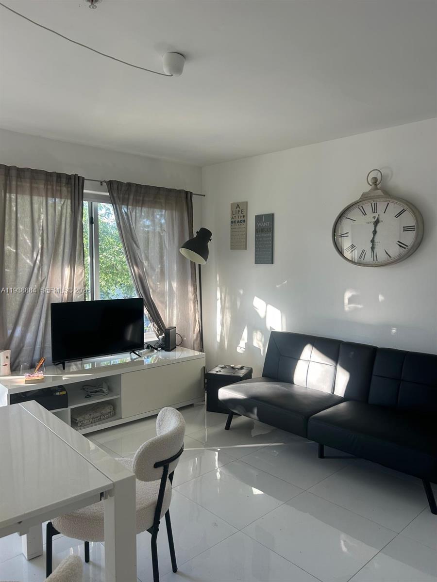A living room features a black sofa, a white media console, and a large wall clock — 801 15th St # 202, Miami Beach FL 33139, MIAMI BEACH, FL