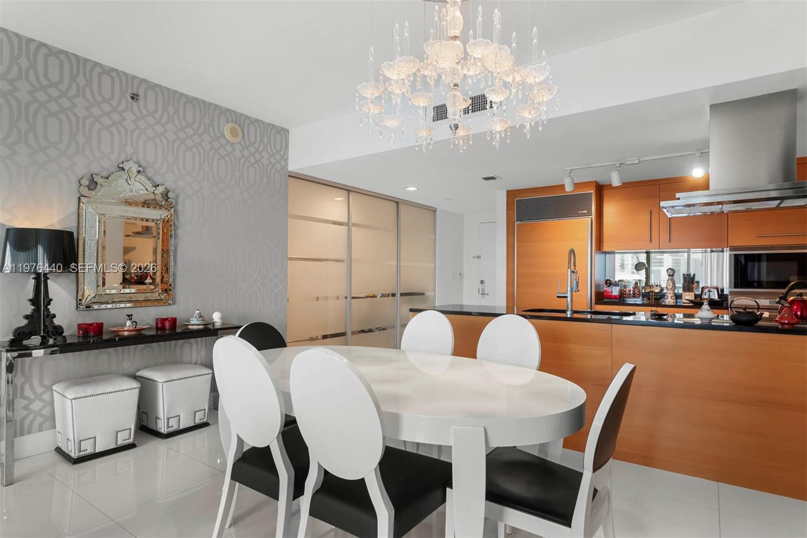 A dining area with a white oval table, chandelier, and adjacent kitchen with wood cabinets — 495 Brickell Ave # 805, Miami FL 33131, MIAMI, FL