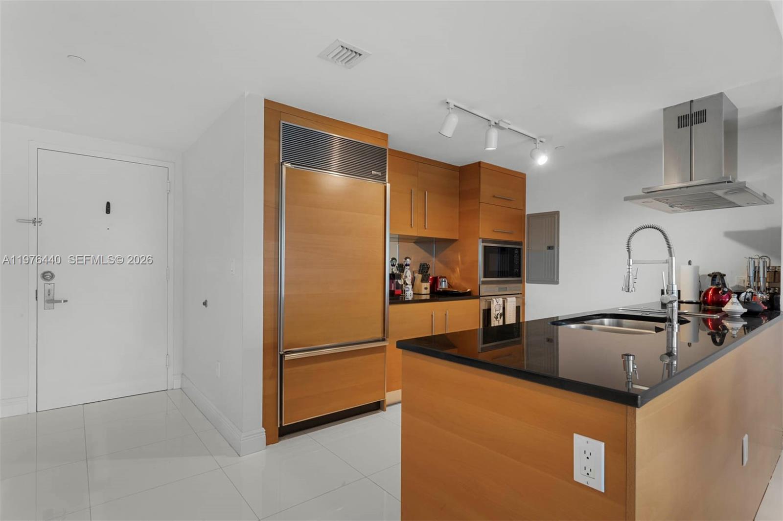 A modern kitchen features wood cabinetry, a black countertop island, and stainless steel appliances — 495 Brickell Ave # 805, Miami FL 33131, MIAMI, FL
