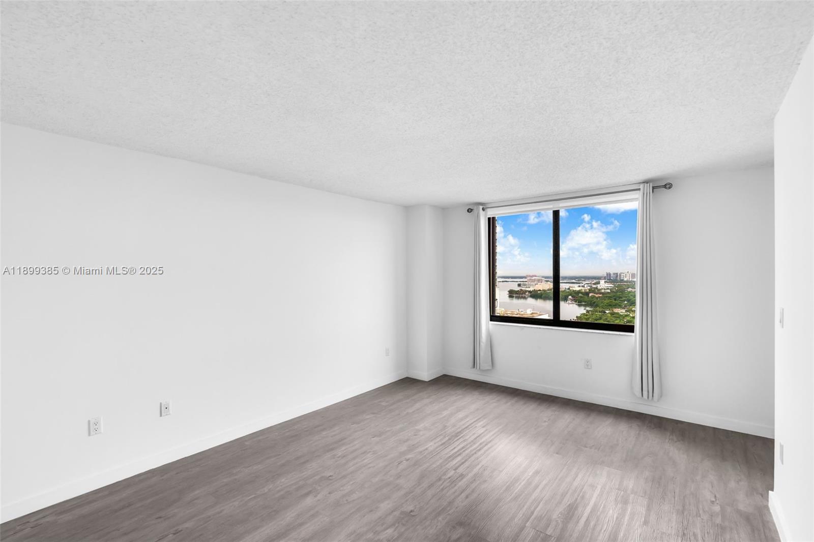 An empty room features white walls, gray wood-look flooring, and a window with a view — 2333 Brickell Ave, Miami FL 33129, MIAMI, FL
