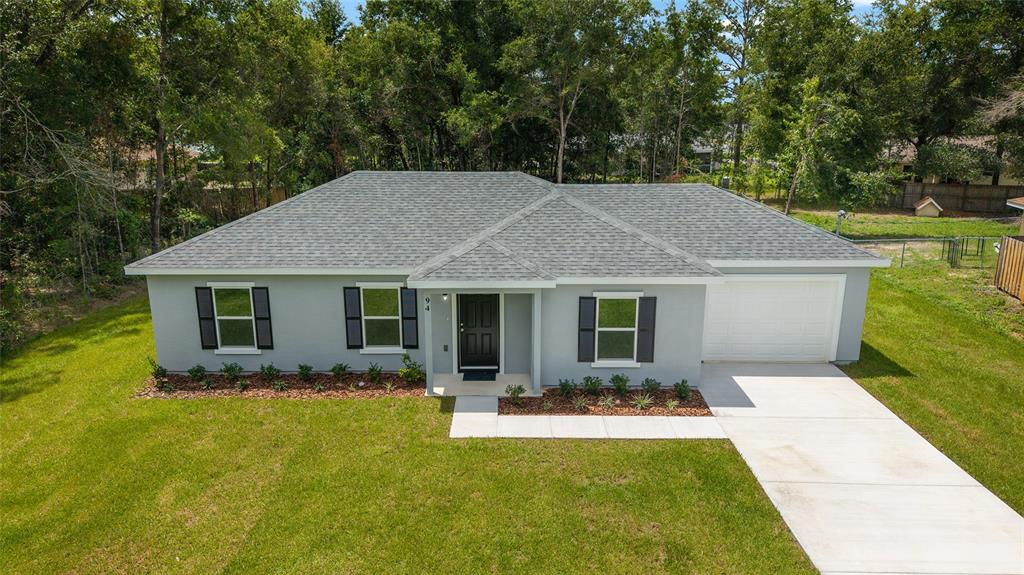A single-story house with a gray exterior, dark shutters, and a concrete driveway — 94 DOGWOOD DRIVE LOOP, OCALA, FL