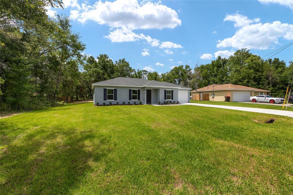 A single-story gray house with black shutters sits on a large, grassy lot — 94 DOGWOOD DRIVE LOOP, OCALA, FL