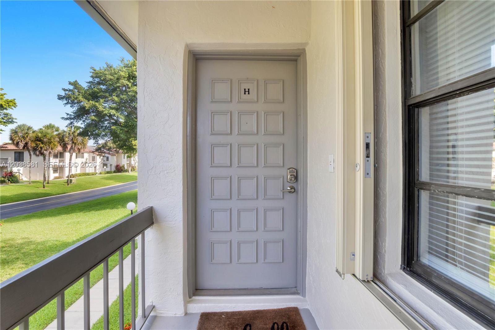 A gray front door with a letter H sits on a covered outdoor balcony — 21650 Juego Cir # 24H, Boca Raton FL 33433, BOCA RATON, FL