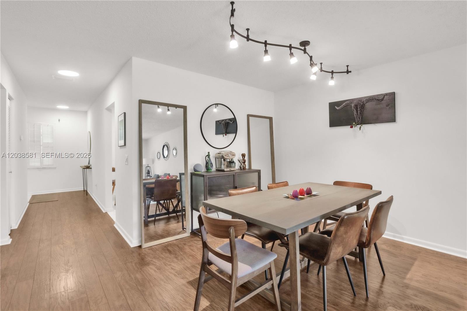 A dining room features a wooden table, six chairs, a sideboard, and a track lighting fixture — 21650 Juego Cir # 24H, Boca Raton FL 33433, BOCA RATON, FL