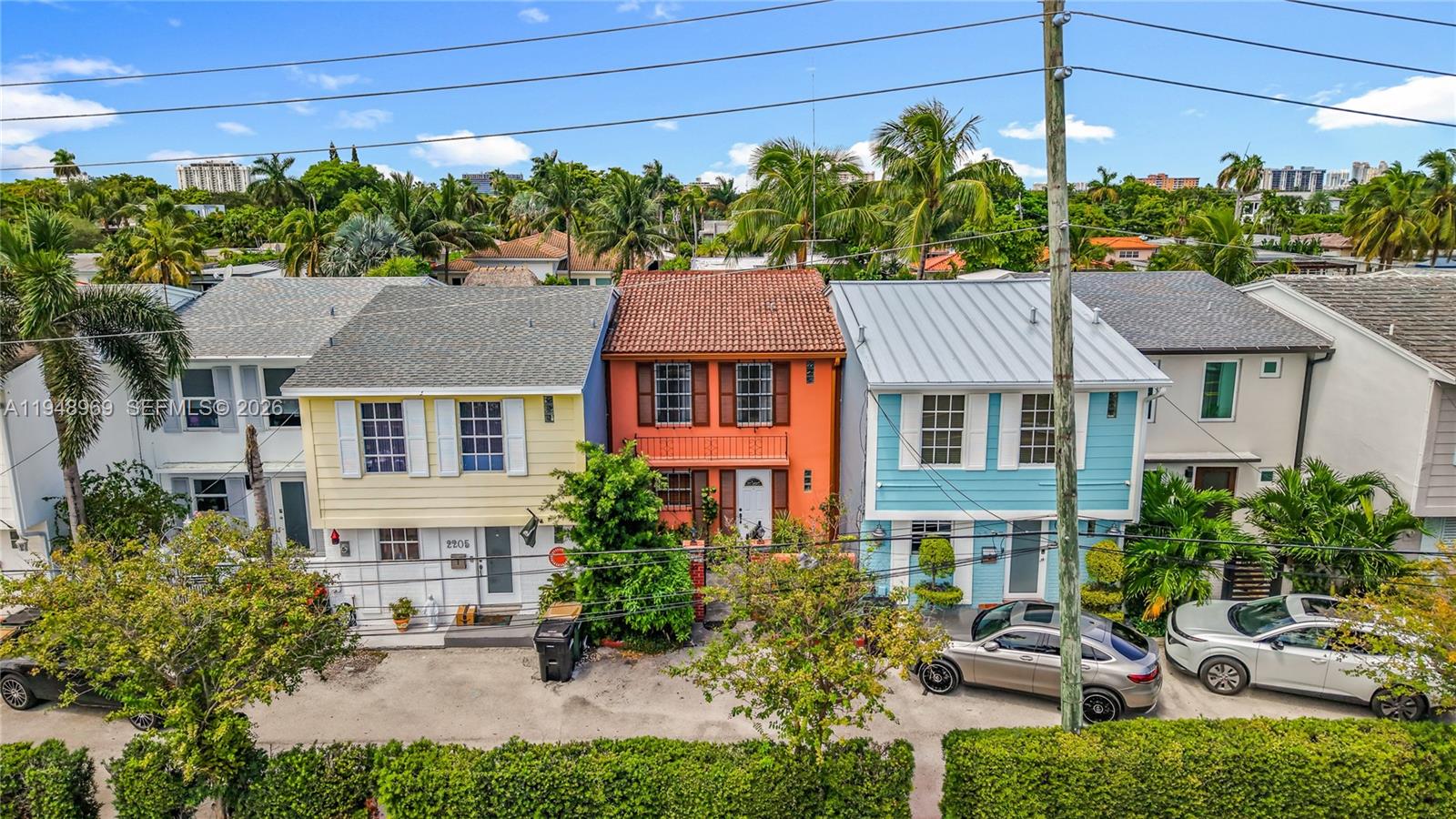An elevated exterior view shows a row of colorful townhouses with palm trees and cars — 2205 NE 123rd St, North Miami FL 33181, NORTH MIAMI, FL