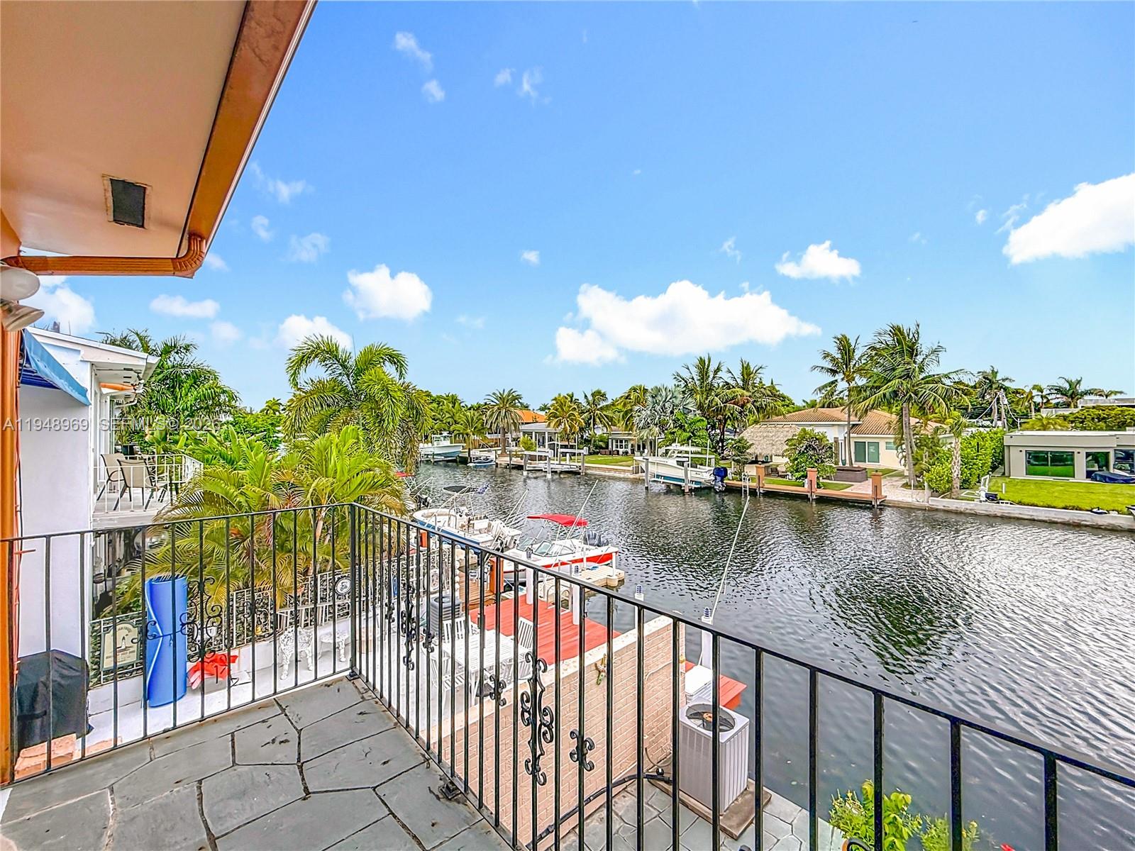 A balcony with a black metal railing overlooks a canal lined with boats and houses — 2205 NE 123rd St, North Miami FL 33181, NORTH MIAMI, FL